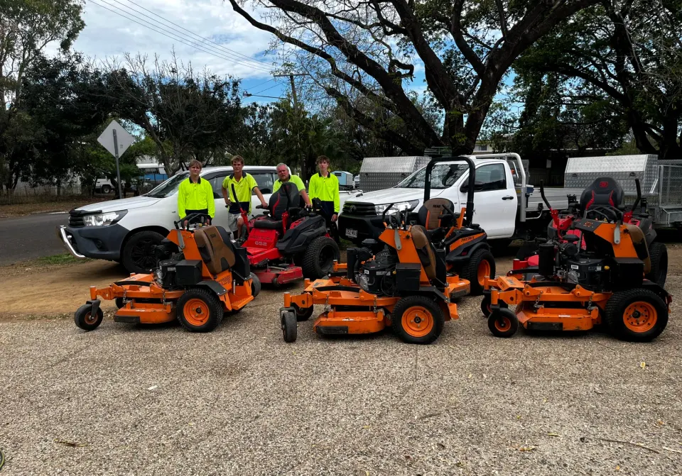 The Triple Sweep team in hi-vis with their commercial mowers and work utes in Townsville