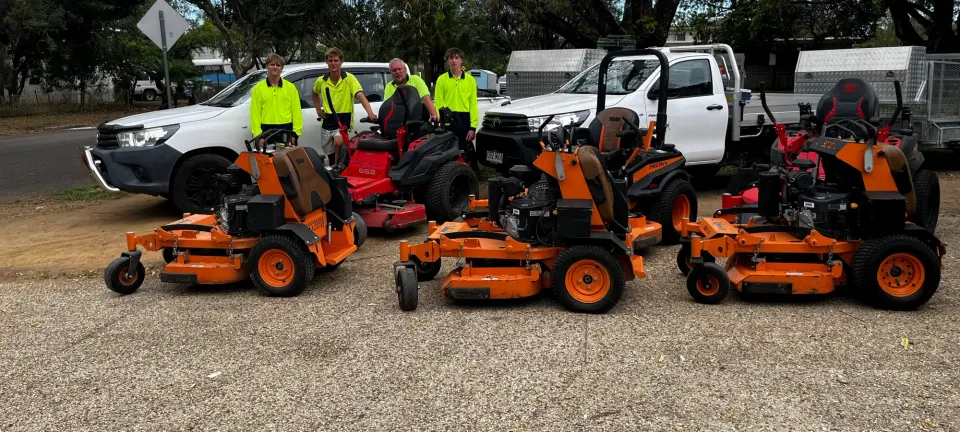 The Triple Sweep team standing behind their row of stand-on and ride-on mowers